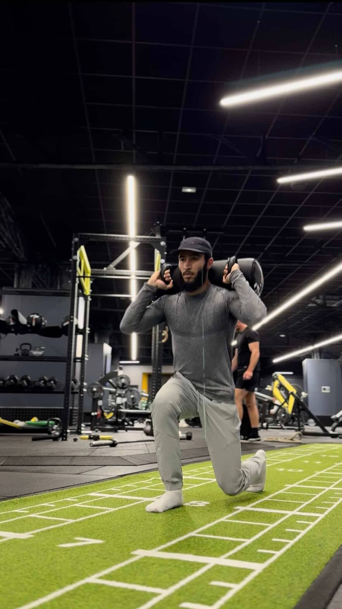 Coach effectuant des fentes avec poids en salle